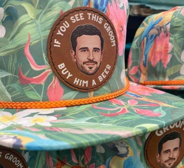 Tropical print rope caps with a leather patch showing a groom caricature and the words if you see this groom buy him a beer.